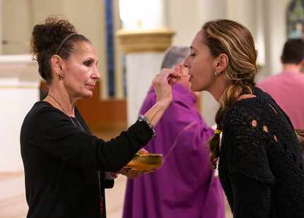 Gloria Figueroa (left) gives communion to a member of the Cathedral Shrine of the Virgin of...