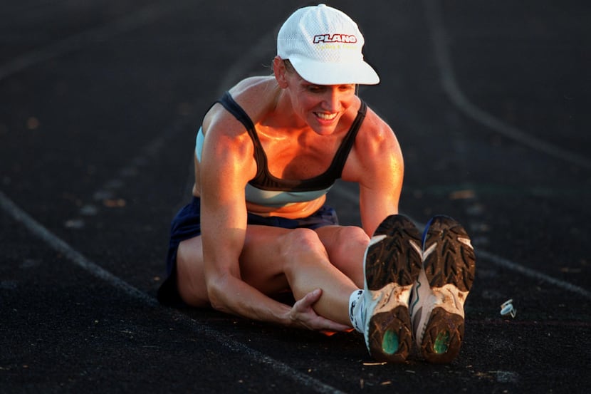 A triathlete stretches after a long run at the Plano Senior High School track.