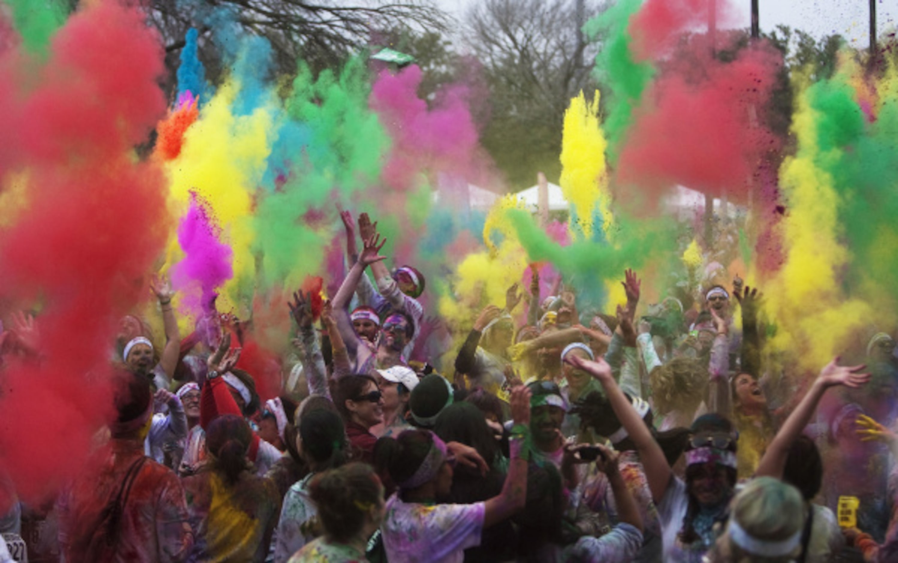 Color Run participants throw colored chalk up in the air after completing the 5K race in...