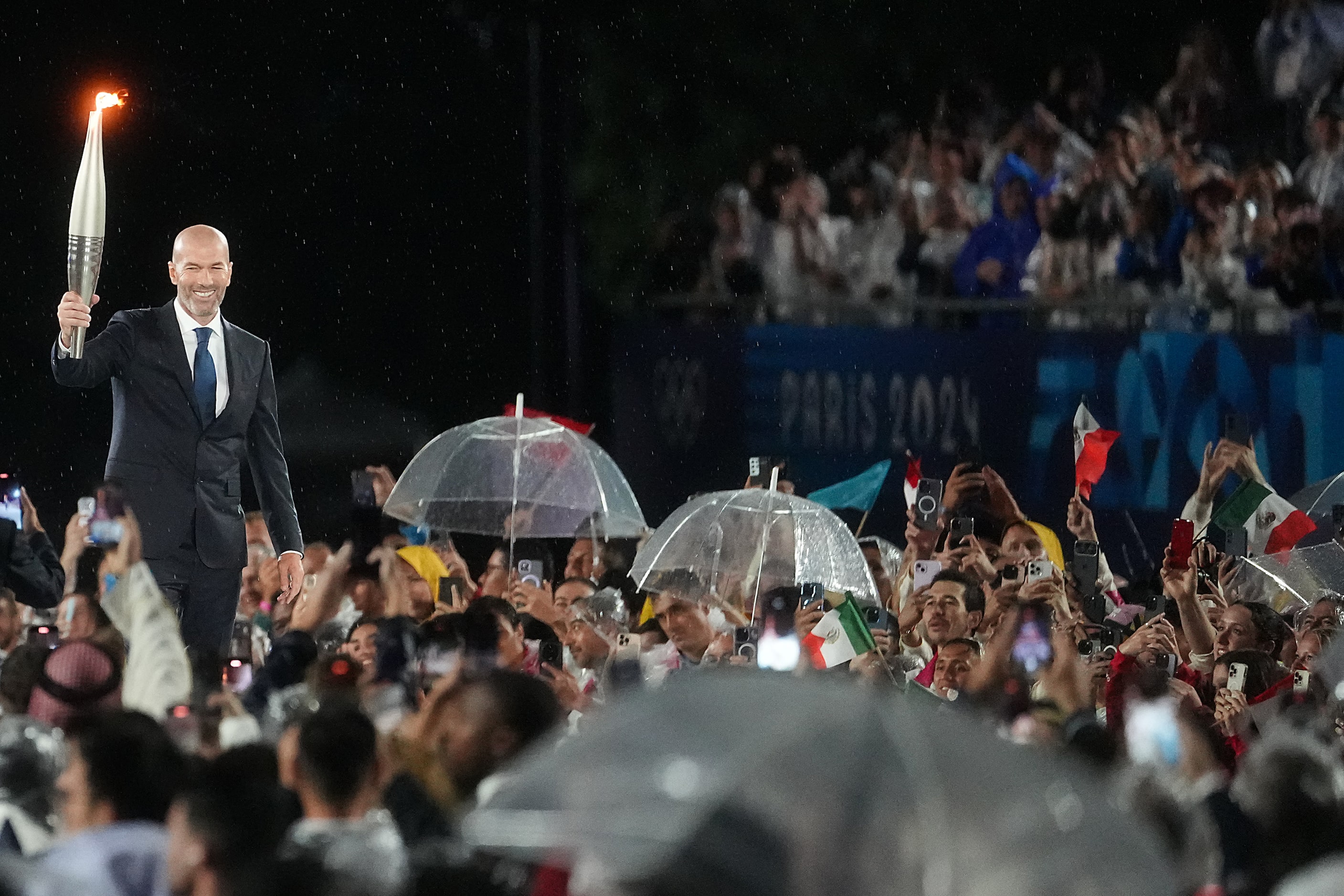 Former French soccer player Zinedine Zidane carries the Olympic Torch during opening...