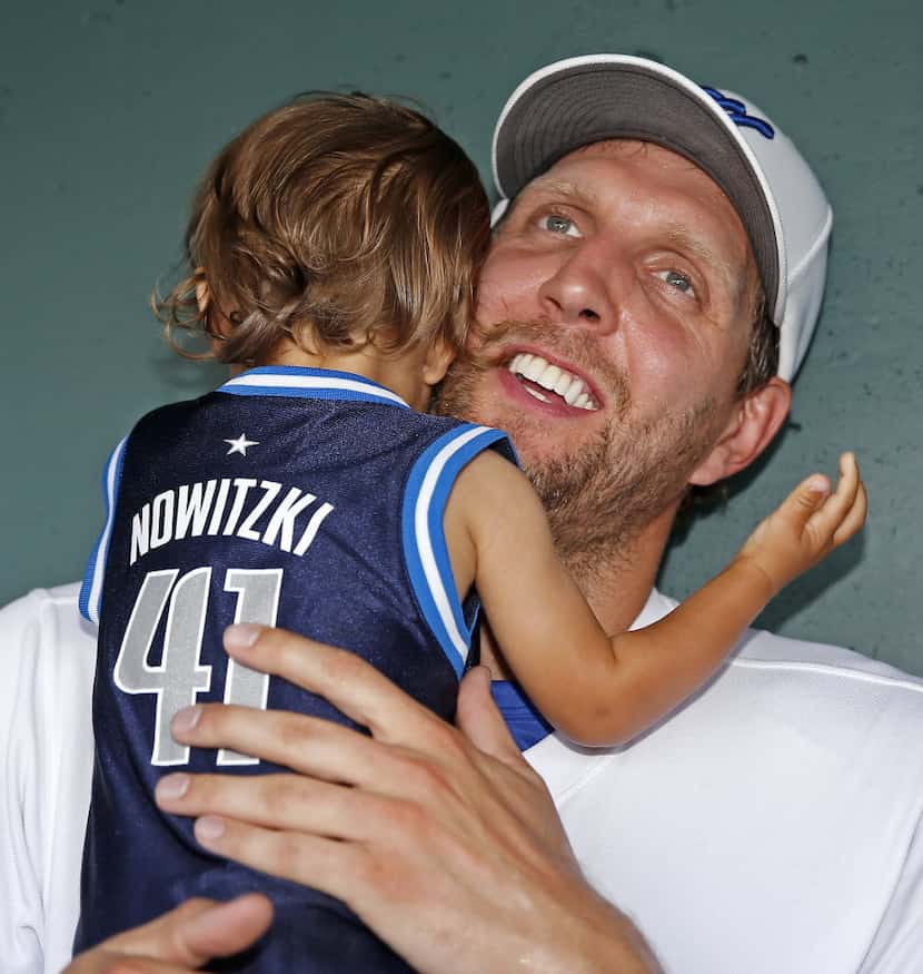 Dallas Mavericks Dirk Nowitzki hugs his 15-month-old son Max Nowitzki in the dugout during...