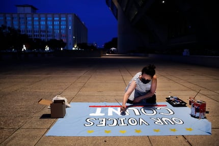 A woman paints her sentiments on blue cloth during the rally outside Dallas City Hall.