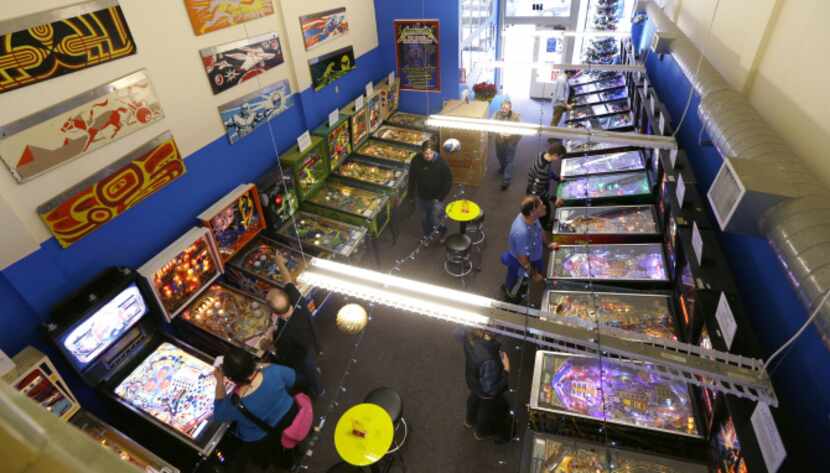 In this Dec. 16, 2013 photo, modern pinball machines line the wall at right while older...
