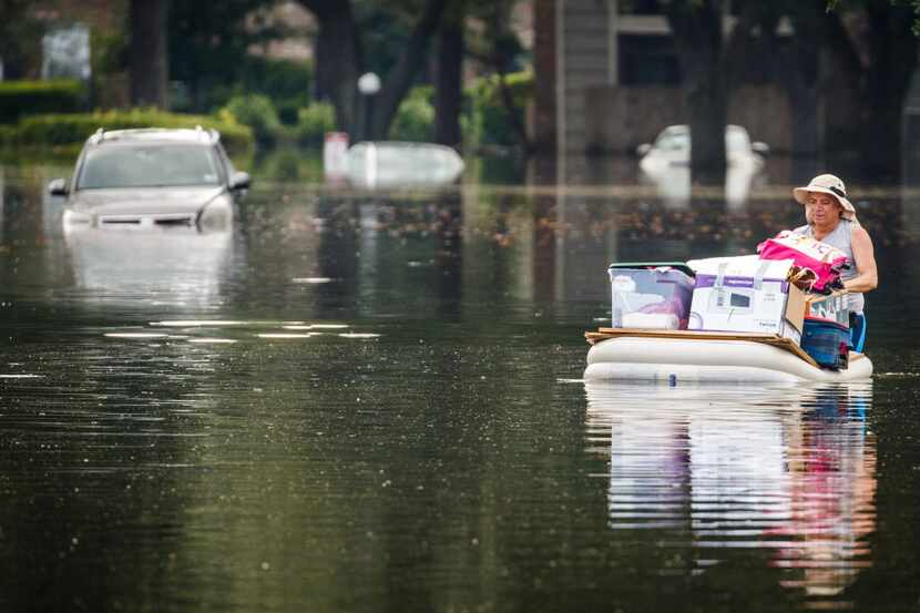 Robin Cardona retrieves belongings from his west Houston apartment through flood water from...