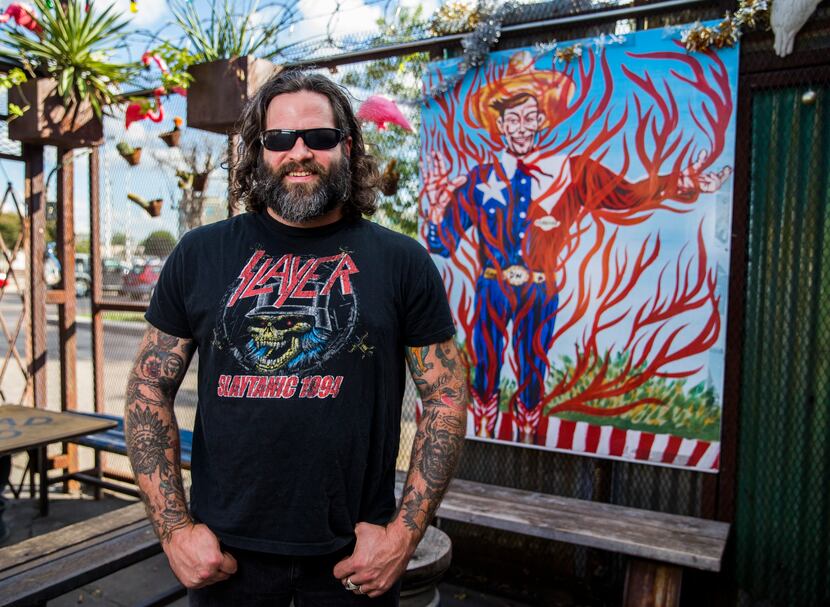 Artist Clay Stinnett with a print of his original flame-themed Big Tex painting at Double...