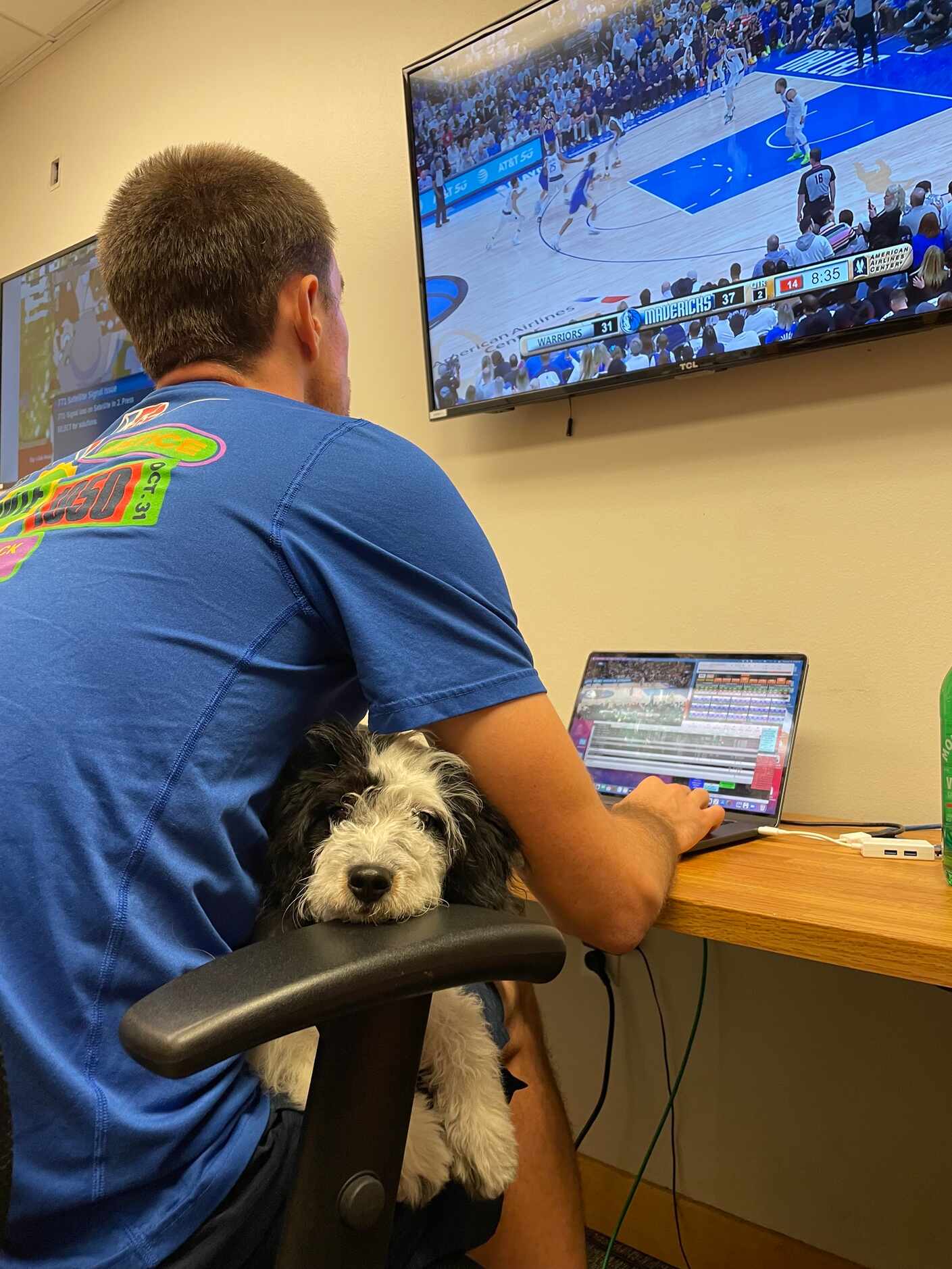 Mavs head video coordinator Max Hooper with emotional support dog Bailey in his lap.