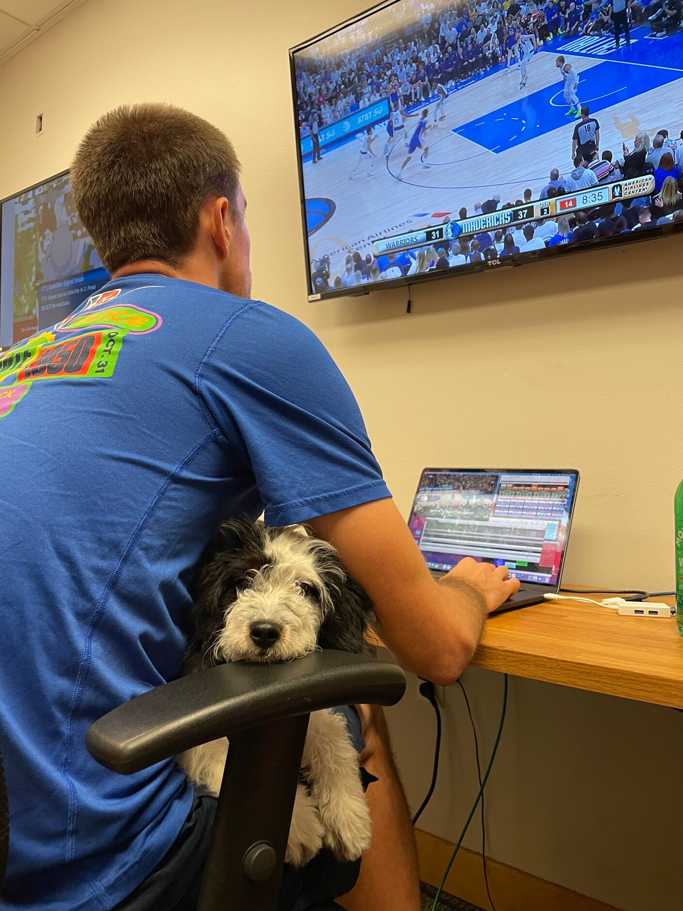 Mavs head video coordinator Max Hooper with emotional support dog Bailey in his lap.