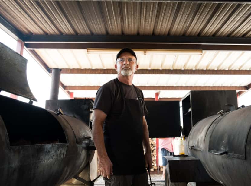 Pitmaster and owner Kirby Hyden poses between the dual offset wood-burning smokers at...