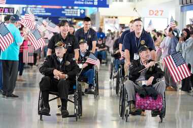 World War II veterans Art Leach, front right, and Henry Armstrong, front left, are pushed...