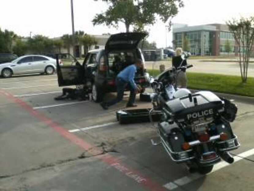 Garland Police Officer R.P. Clark reaches beneath the sport utility vehicle to loosen the...