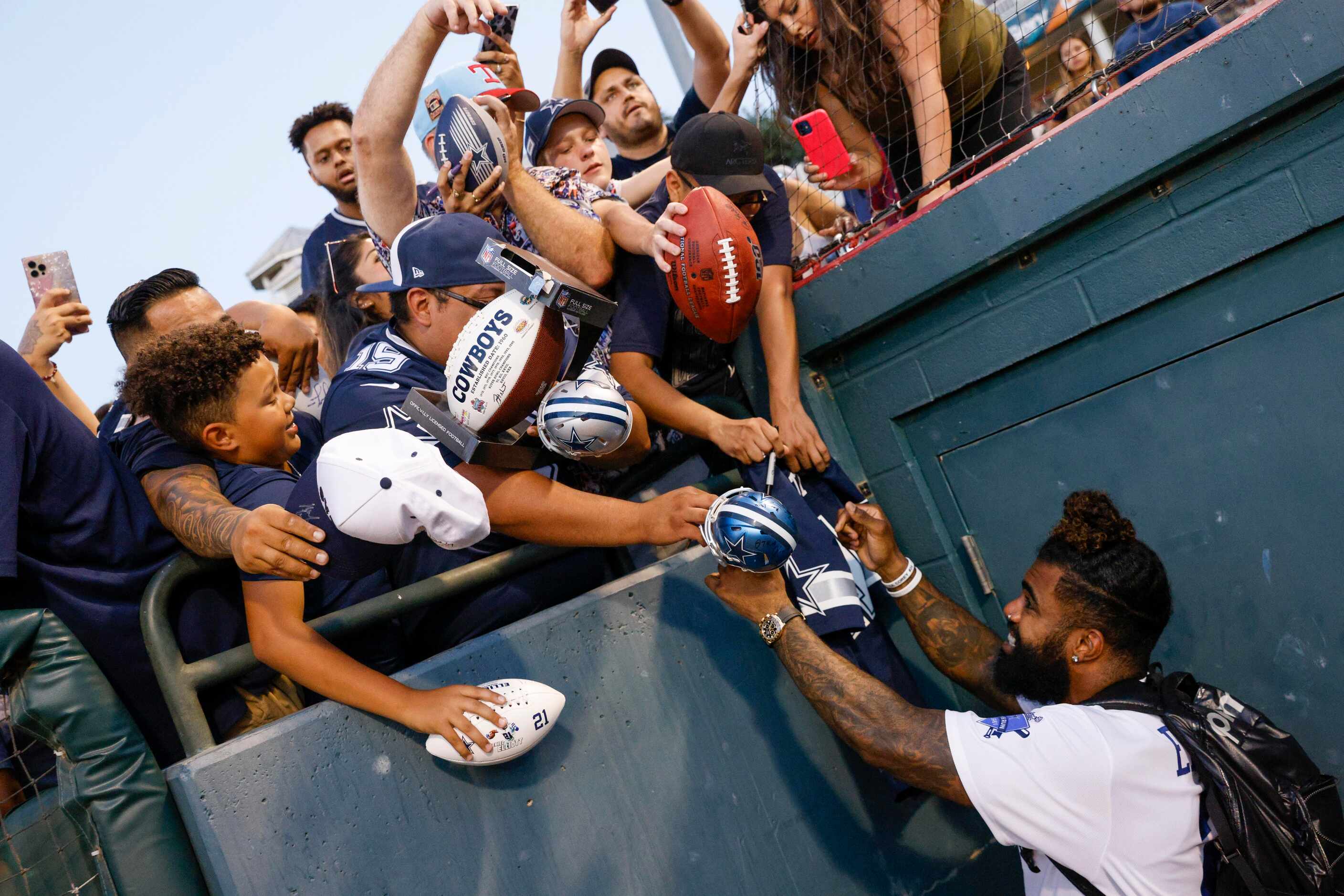 Dallas Cowboys running back Ezekiel Elliott signs autographs from the dugout after the...