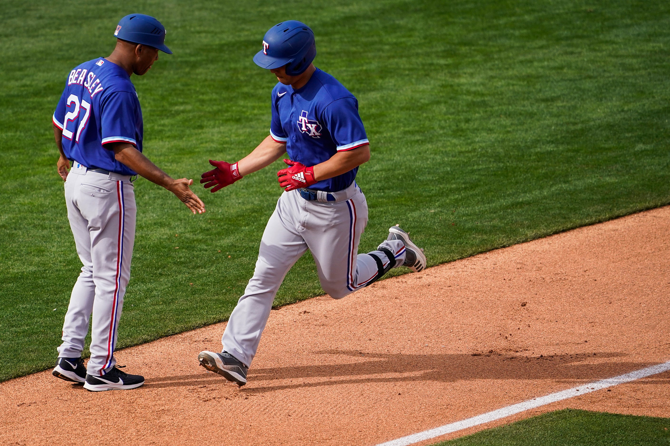 Texas Rangers outfielder Rob Refsnyder celebrates with third base coach Tony Beasley as he...