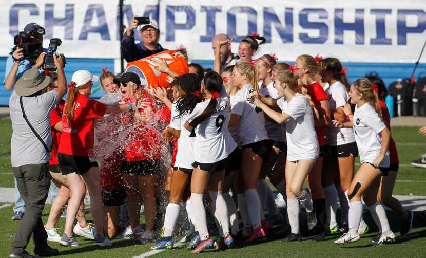 Flower Mound Marcus head coach Erin Hebert is doused with ice and water from the cooler...