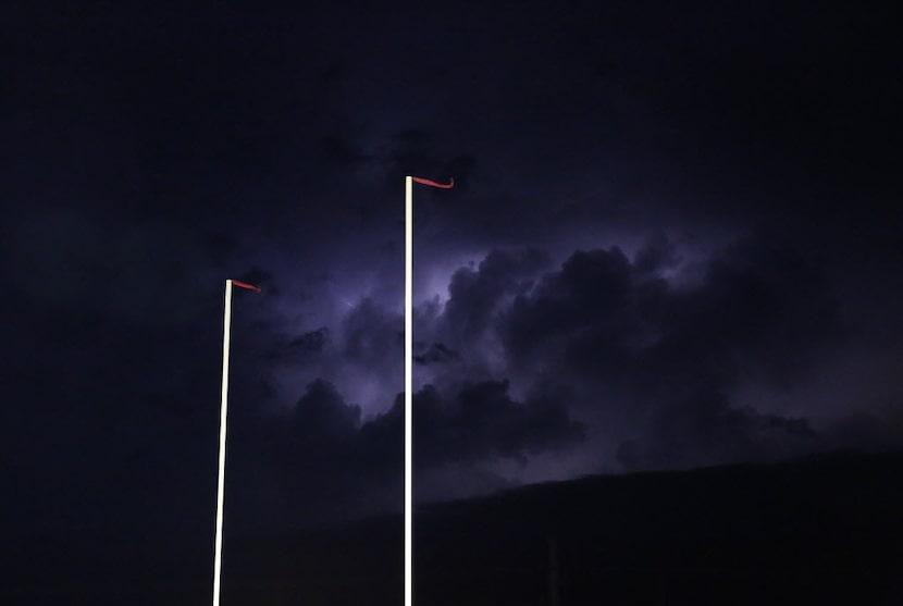 Lightning illuminates the sky as severe weather approaches before a high school football...