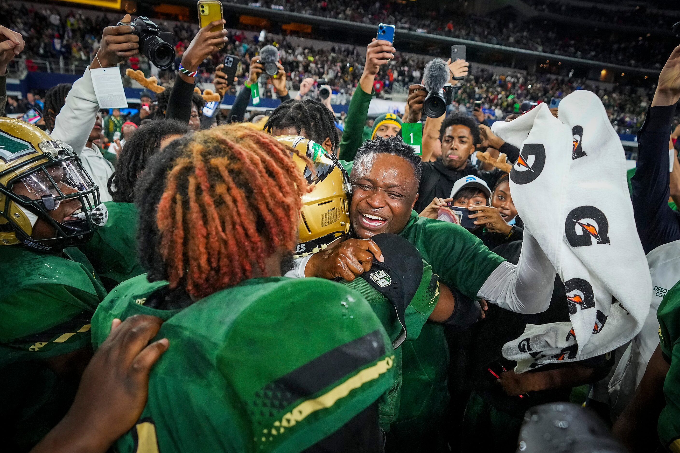 DeSoto head coach Claude Mathis hugs defensive back Caden Mathis (28) as he celebrates with...