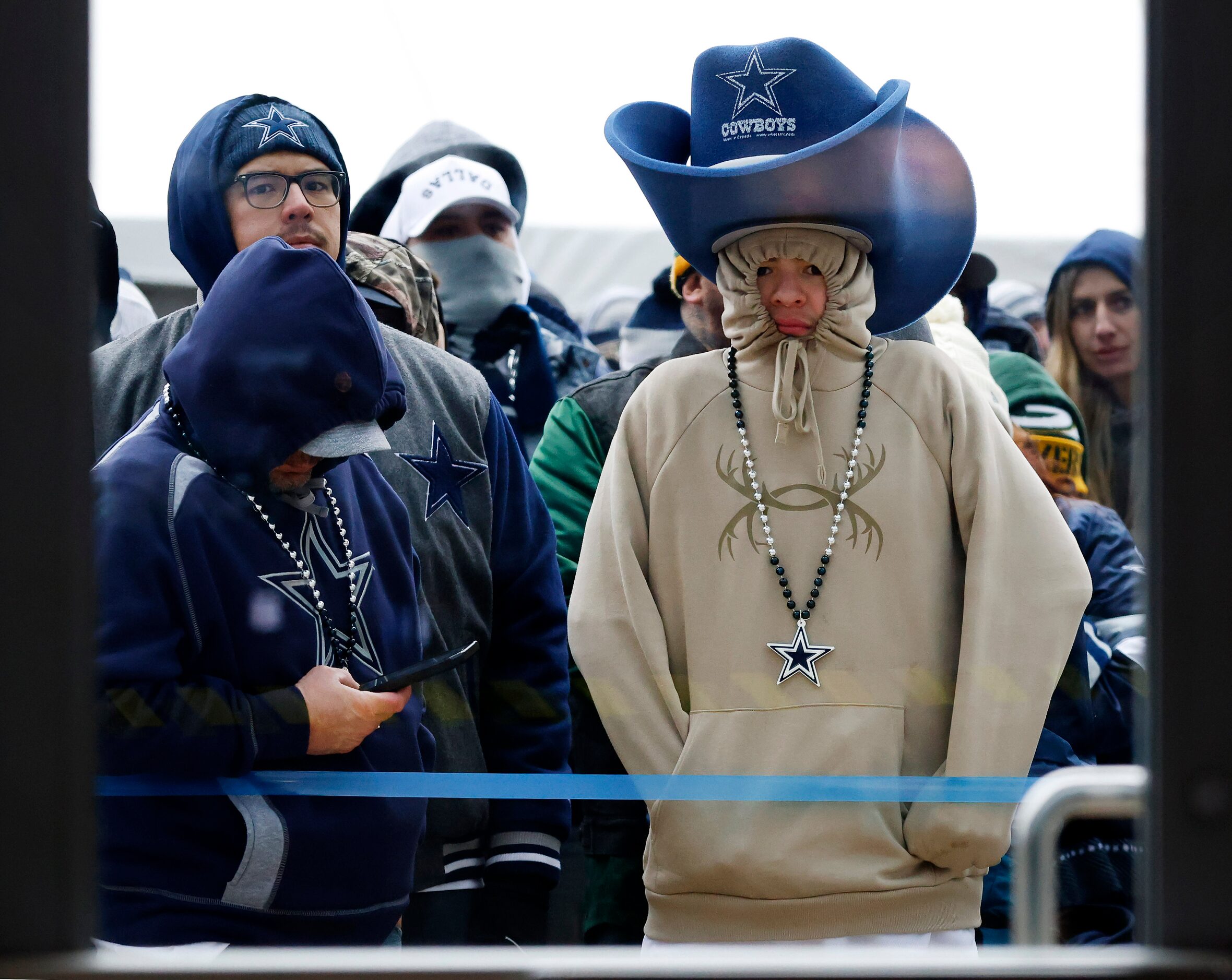 Dallas Cowboys and Green Bay Packers fans keep warm on the west plaza as they wait to get...