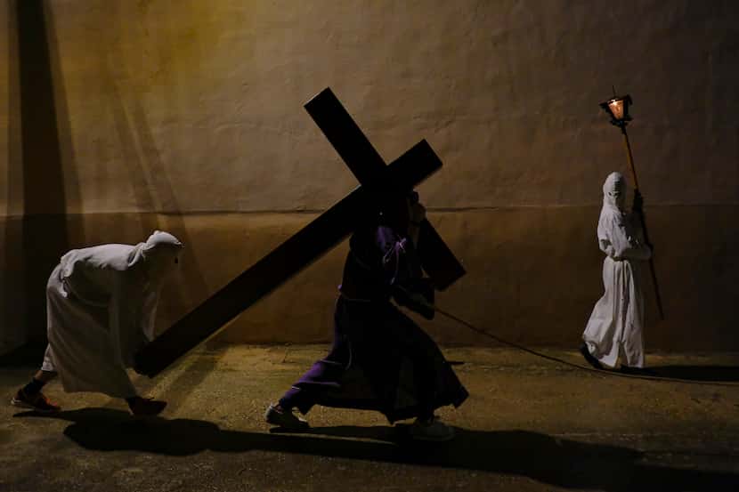 Un penitente encapuchado carga una cruz como parte de la procesión del Viernes Santo en...