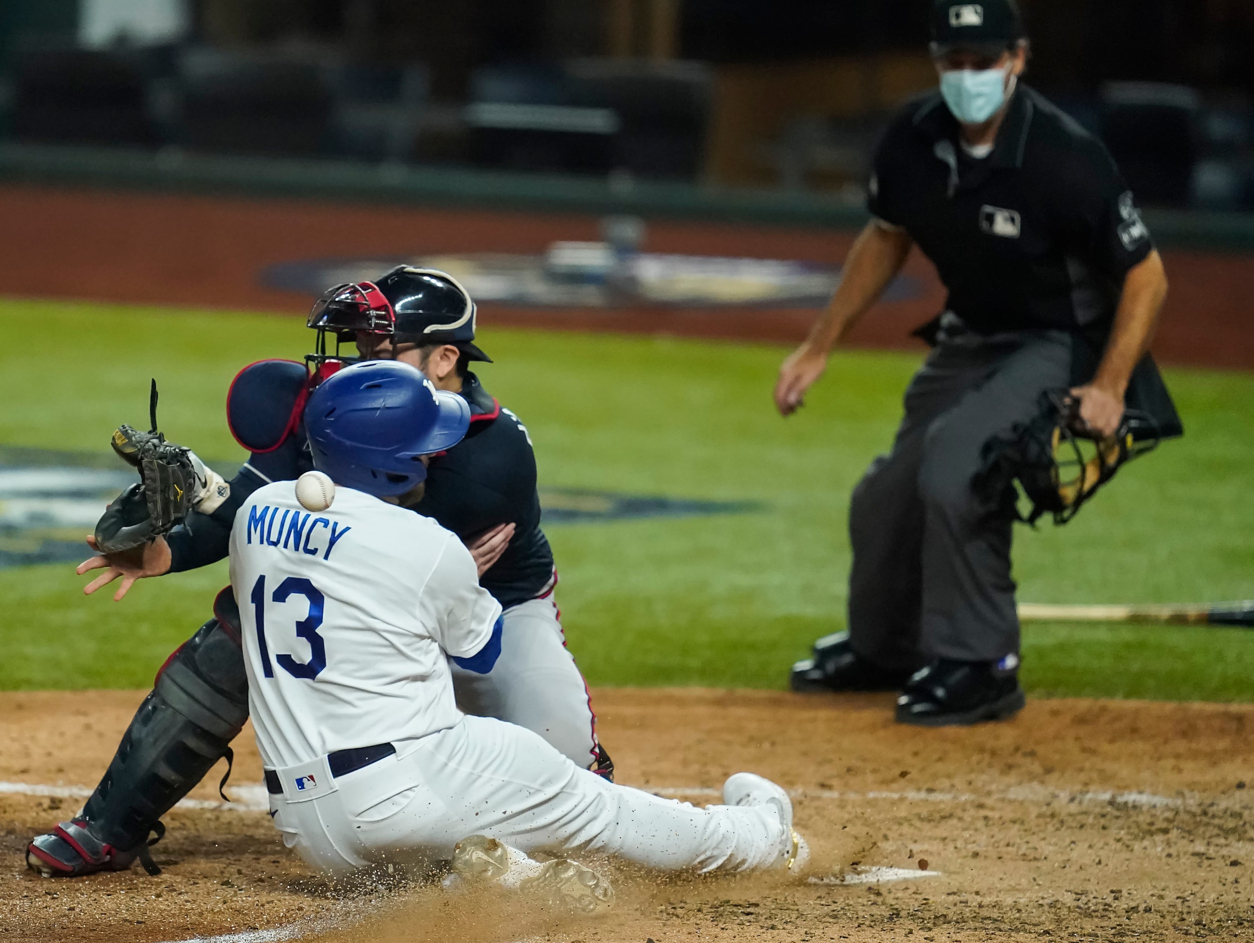 Los Angeles Dodgers first baseman Max Muncy scores past Atlanta Braves catcher Travis...