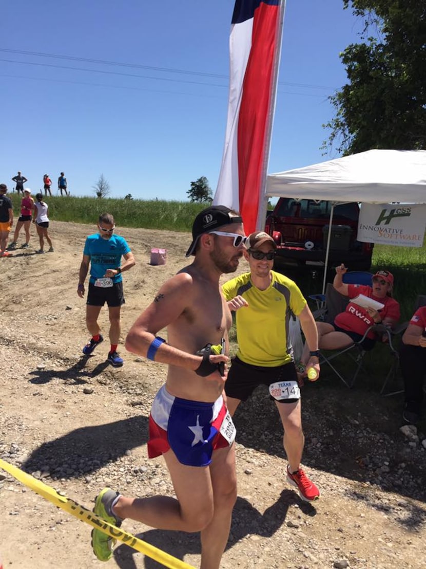 Bryan Barnett shows off his Texas pride with bright running shorts as he hands off the team...