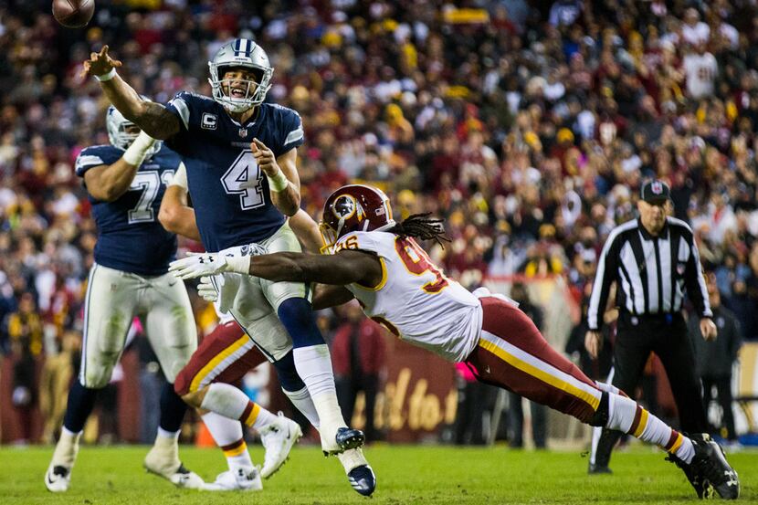 Dallas Cowboys quarterback Dak Prescott (4) throws a pass while being tackled by Washington...