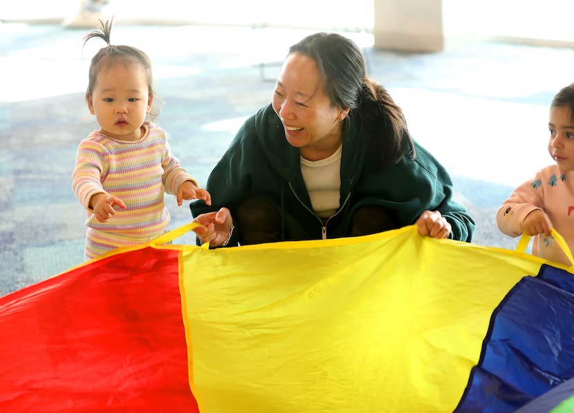 Hope Kim plays with 18-month-old Amélie during Toddler Parachute Play at Harrington Public...