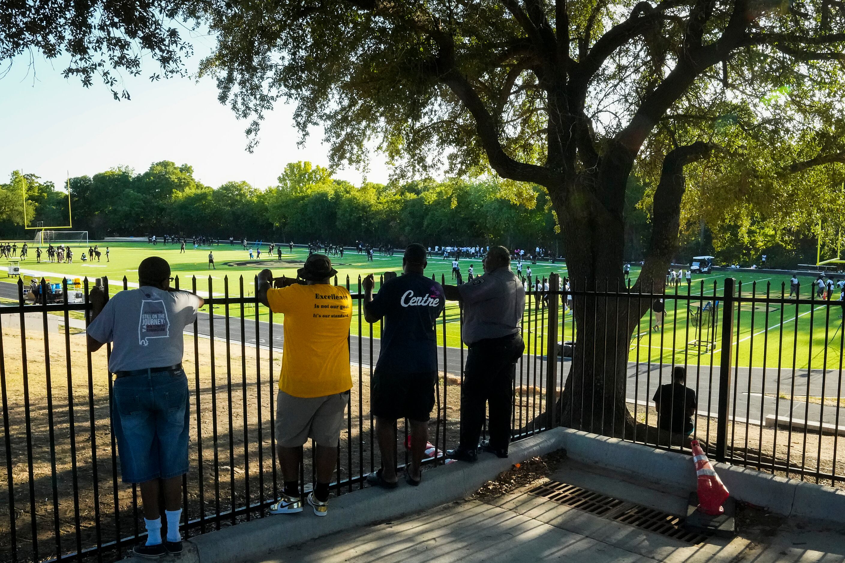 People gather outside the fence to watch the first practice of the season for defending...