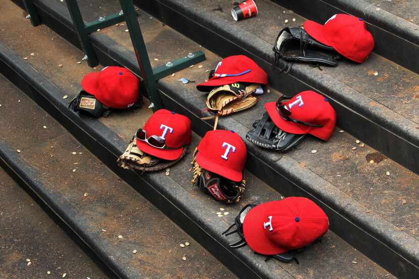 The gloves and hats of the Rangers await their owners on the dugout steps during the Toronto...