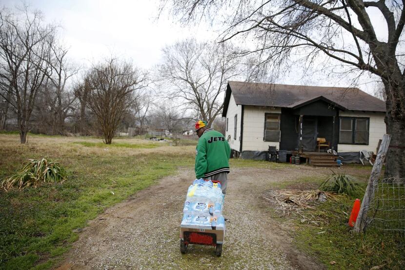 Demetrius X. Blair delivers  bottled water to a home in Sandbranch, which lacks clear...