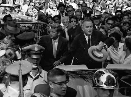 LBJ motions for a path through the 175,000 spectators as the motorcade slows to a crawl at...