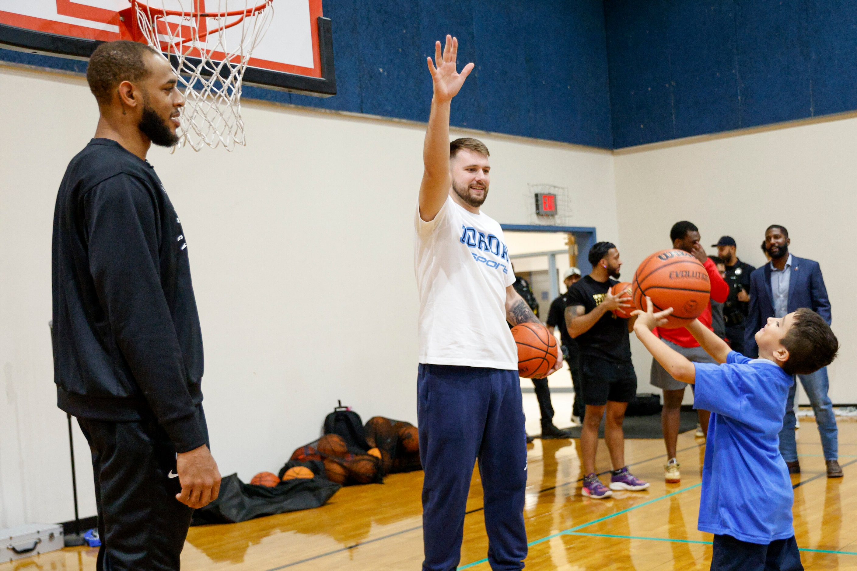 Dallas Mavericks guard Luka Doncic (right) contests a child’s shot attempt alongside center...