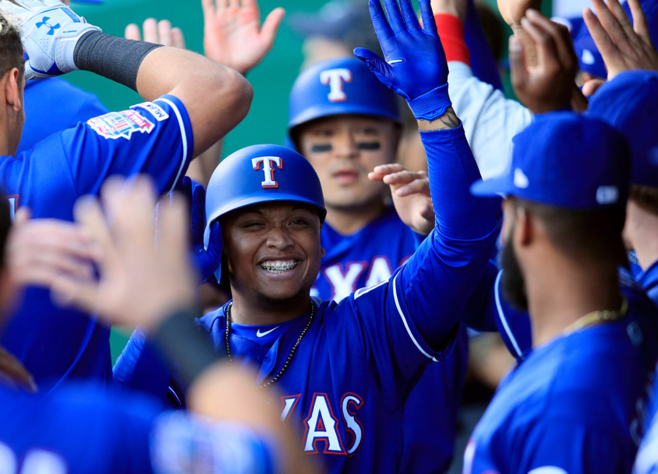 Texas Rangers designated hitter Willie Calhoun is congratulated by teammates after his...