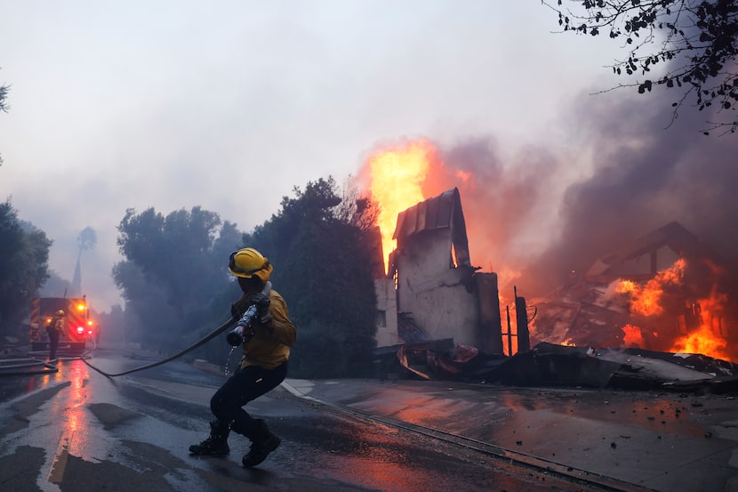 Un bombero intenta contener el avance de un incendio que consume una estructura en Pacific...