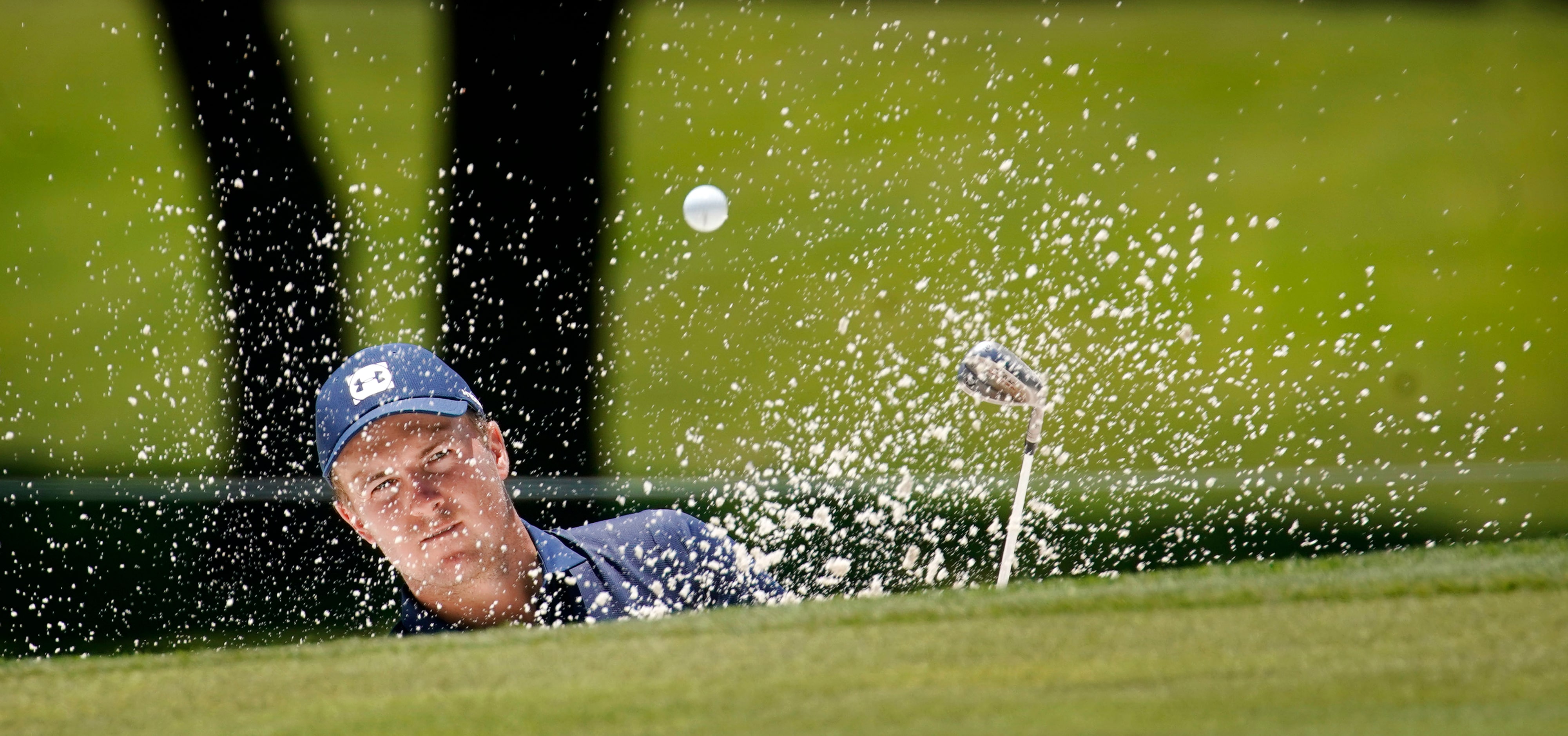 PGA Tour golfer Jordan Spieth splashes his ball out of the greenside bunker on No. 2 during...