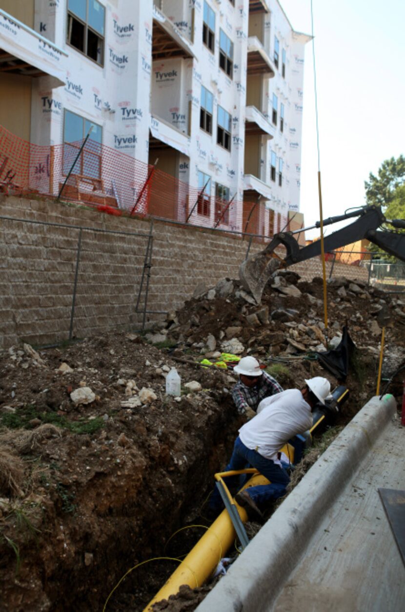 Contract workers for Atmos Energy posltion a polyethylene pipe on Wycliff Avenue near the...