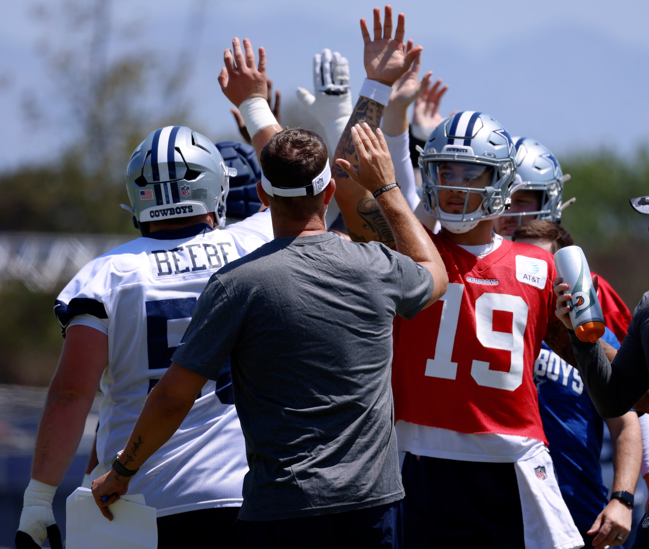 Dallas Cowboys quarterback Trey Lance (19) slaps hands with the centers, fellow quarterbacks...