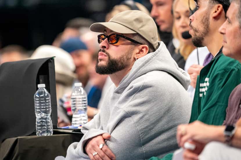 Recording artist Bad Bunny (left) sits courtside during the first half of Game 4 of an NBA...