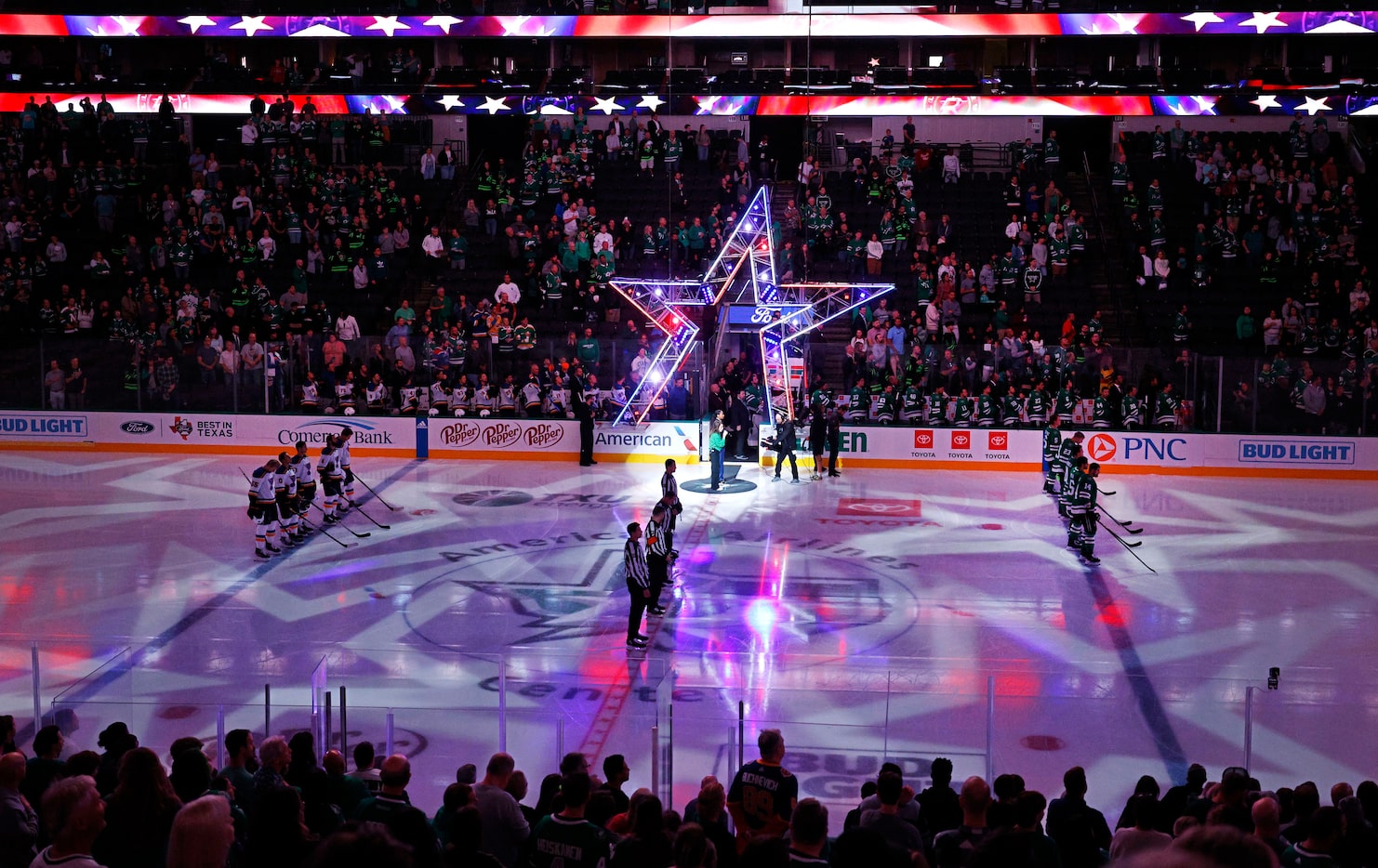 St. Louis Blues and Dallas Stars players stand for the national anthem before a preseason...