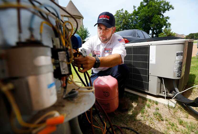 Berkey's technician Brandon Cronkhite adds R-410A refrigerant to an outdoor condensing unit...