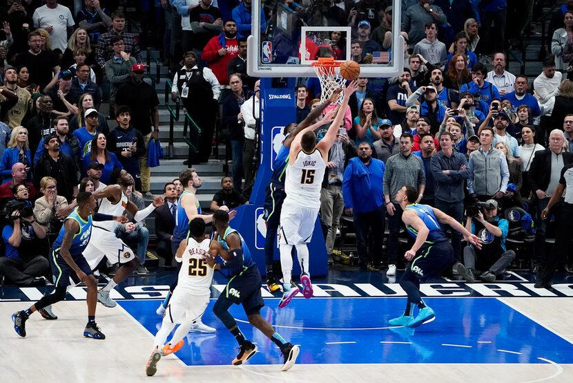 FILE - Nuggets center Nikola Jokic (15) scores over Mavericks forward Dorian Finney-Smith...