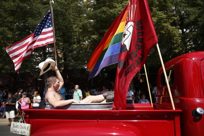 A 'naked' cowboy rides in the back of an old Ford pickup sponsored by the Round-Up Saloon...