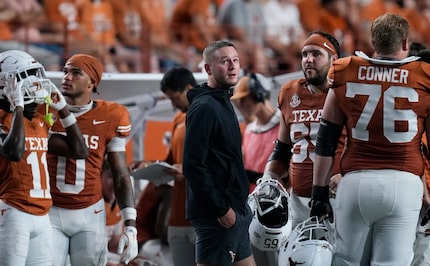 Texas quarterback Quinn Ewers, center, stands on the sidelines in street cloths after he was...