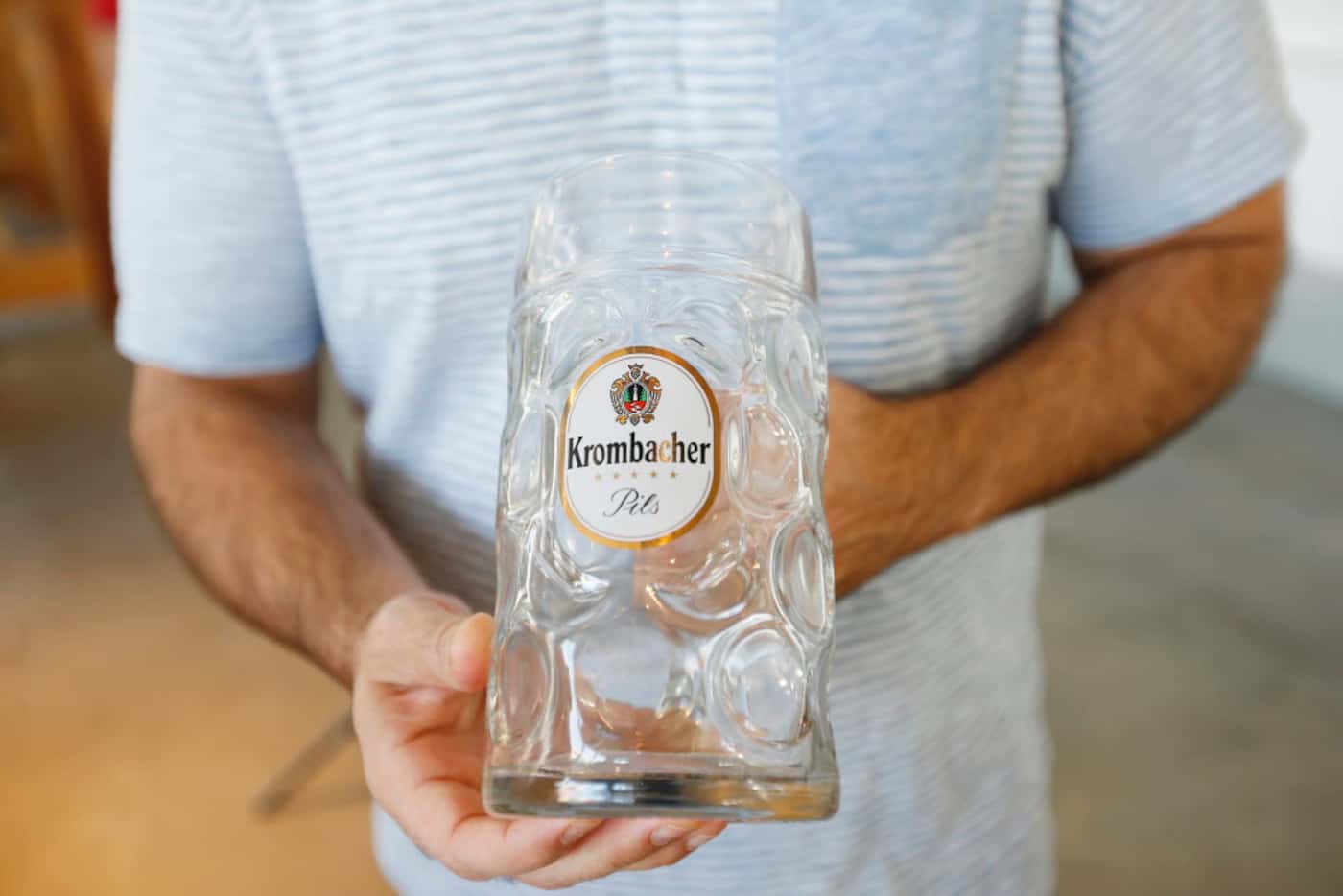 Biergarten Managing Partner Robert Cimillo holds a Krombacher-branded beer mug, one of many...
