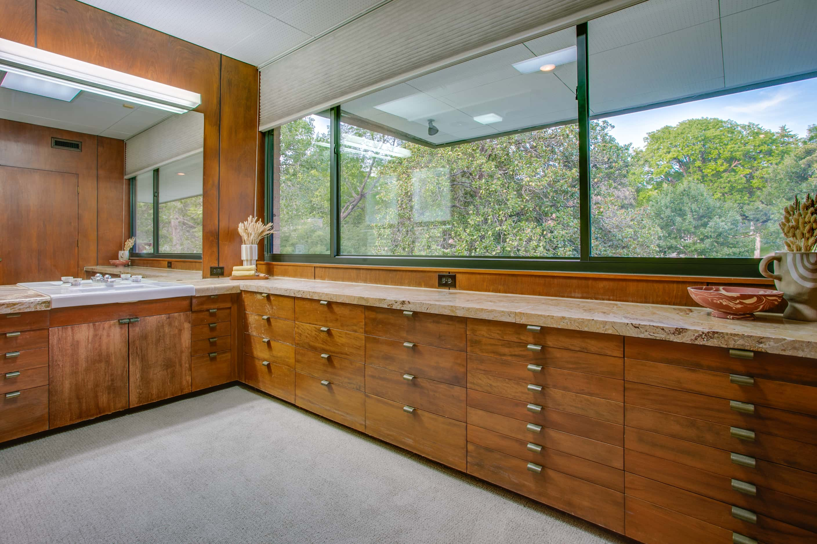 Bathroom with large windows, built in cabinetry, wood design elements