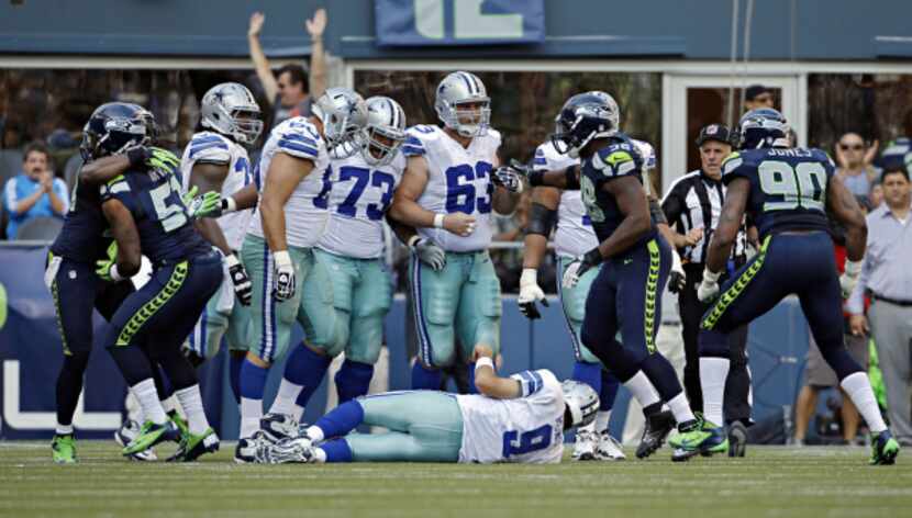Dallas Cowboys quarterback Tony Romo lays on the ground as Seattle Seahawks react after...