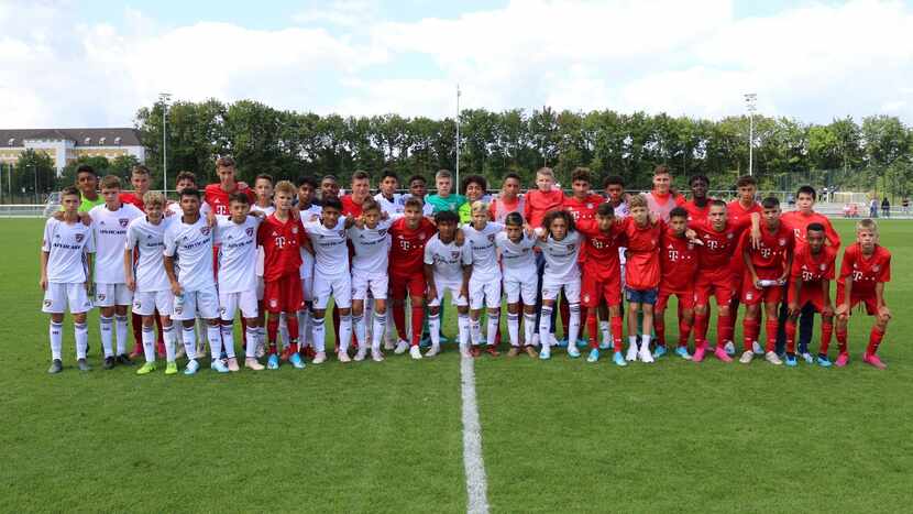 The FC Dallas U15s (in white) pose with the Bayern Munich U15s (in red) after their opening...