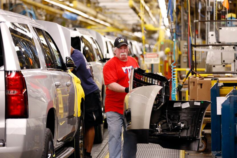  General Motors worker Daniel McGee carries a bumper part of a new GM SUV while he works at...