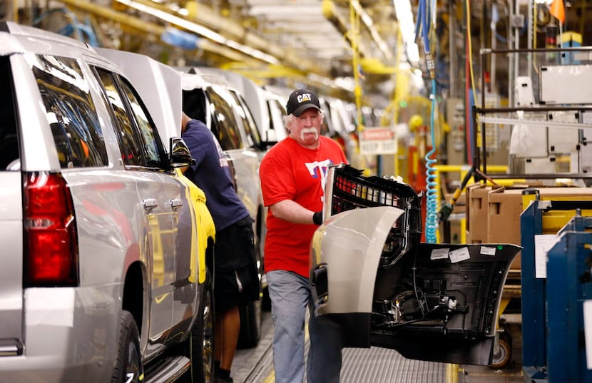  General Motors worker Daniel McGee carries a bumper part of a new GM SUV while he works at...