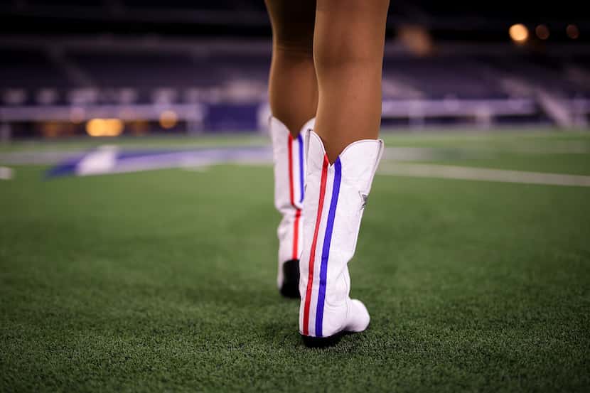 Una porrista de los Cowboys de Dallas modela botas con una raya roja distintiva. Las...