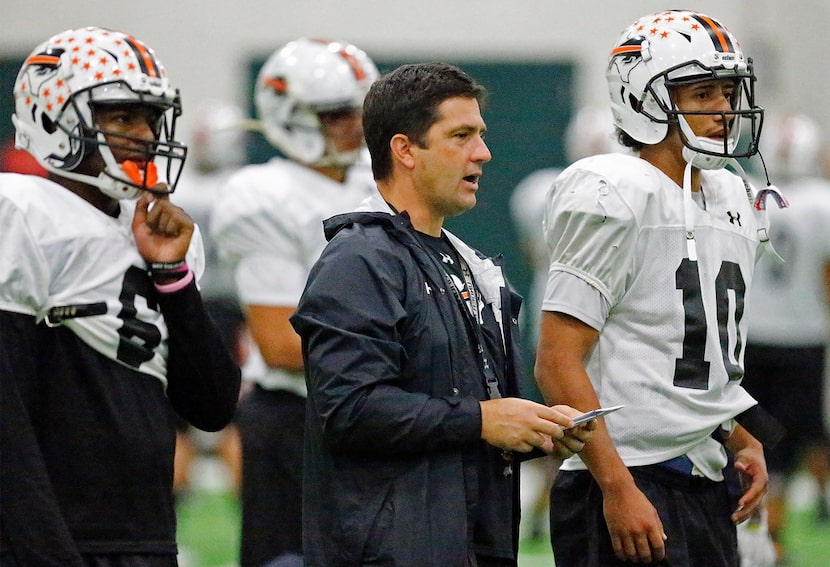 Haltom High School head coach Jason Tucker (center) stands between running back Kenneth...