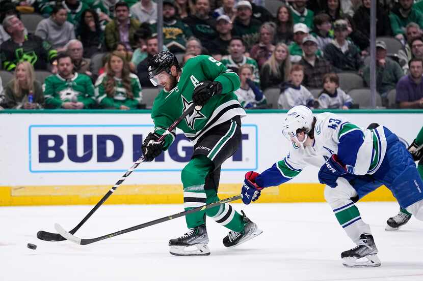 Dallas Stars center Tyler Seguin (91) shoots as Vancouver Canucks' Quinn Hughes (43) defends...